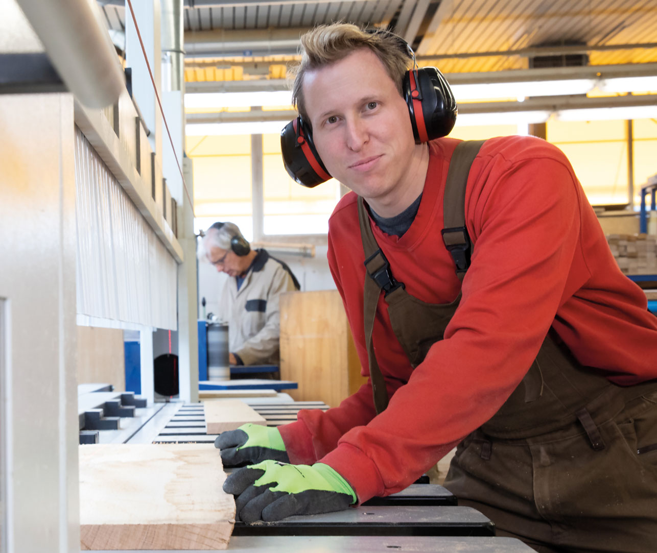 Ein lächelnder Arbeiter sägt mit einer Maschine präzise Holz